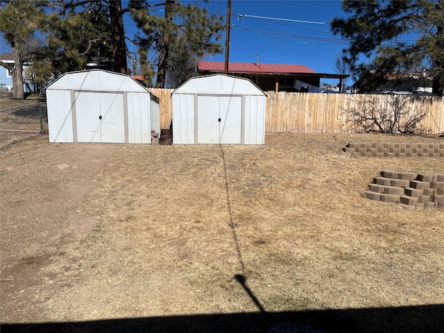 view of yard with a fenced backyard, a storage unit, and an outbuilding