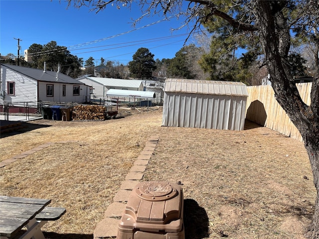 view of yard featuring a storage shed, a fenced backyard, and an outbuilding