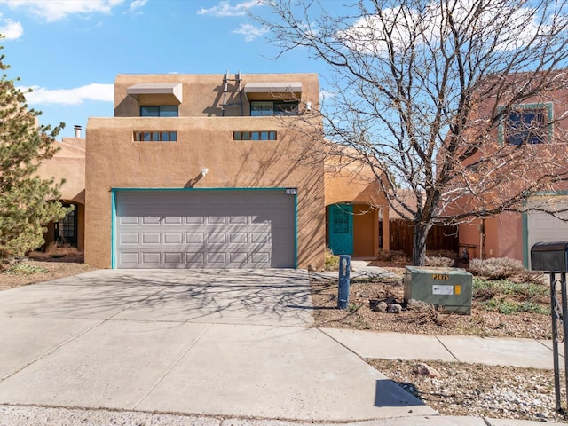 adobe home with a garage, concrete driveway, and stucco siding