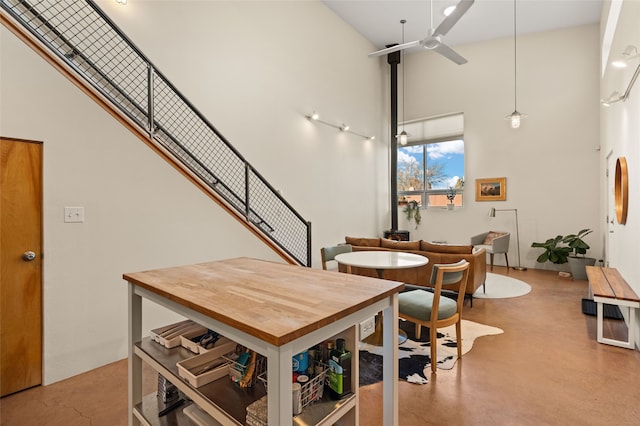 dining room featuring concrete floors, a high ceiling, and a ceiling fan