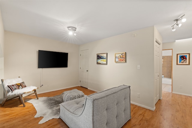 living room featuring light wood-style floors, rail lighting, and baseboards