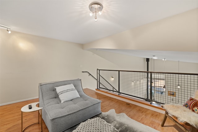 living area with lofted ceiling, baseboards, an upstairs landing, and wood finished floors