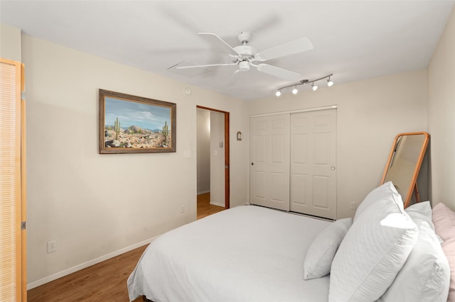 bedroom featuring a ceiling fan, a closet, baseboards, and wood finished floors