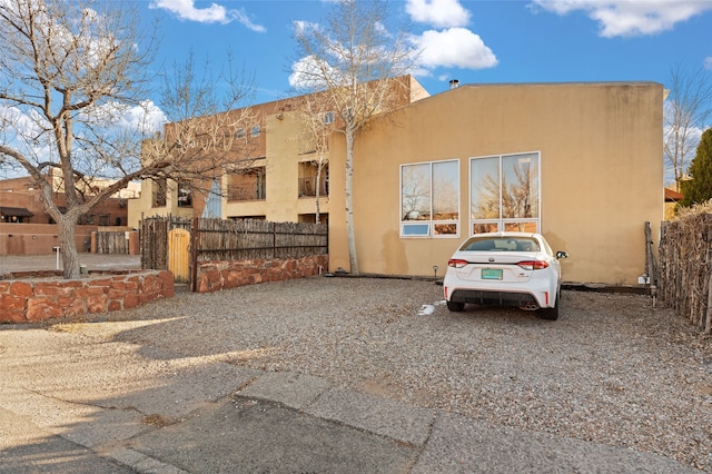 view of front of property featuring a gate, fence, and stucco siding