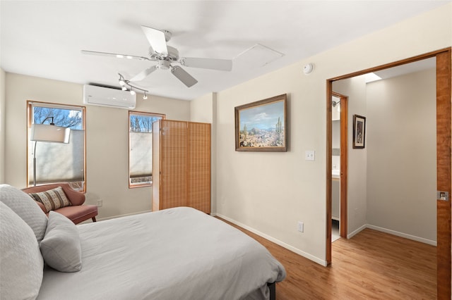 bedroom featuring a wall mounted air conditioner, ceiling fan, baseboards, and wood finished floors