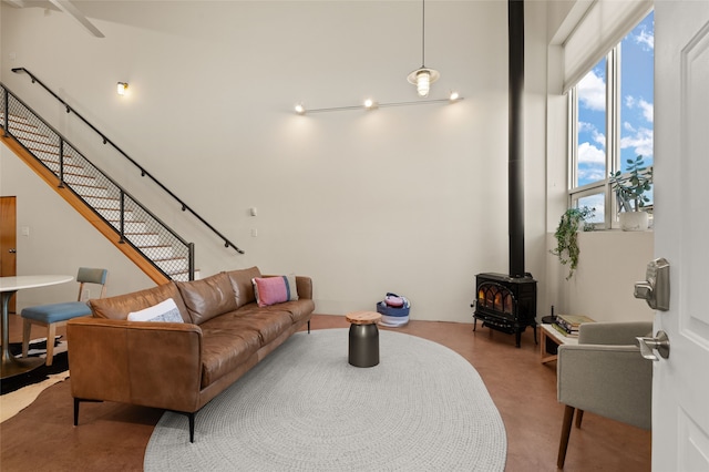 living area featuring a wood stove, a high ceiling, and stairway