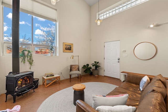 living room with a wood stove and a towering ceiling