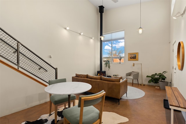 living room featuring a wood stove, concrete floors, and a towering ceiling