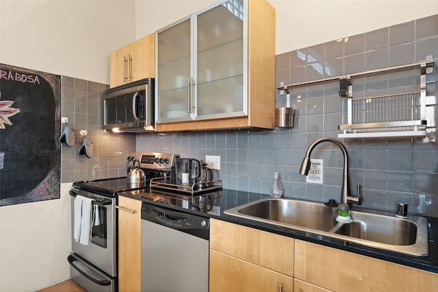 kitchen featuring appliances with stainless steel finishes, light brown cabinets, a sink, and decorative backsplash