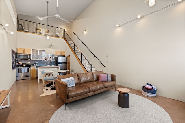 living room with high vaulted ceiling, a ceiling fan, concrete floors, and stairs