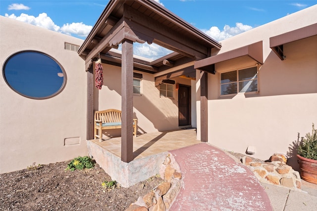 view of exterior entry featuring visible vents and stucco siding