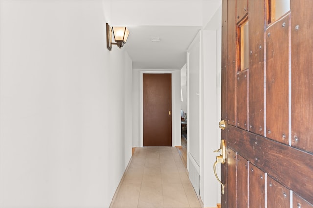 corridor with baseboards and light tile patterned flooring