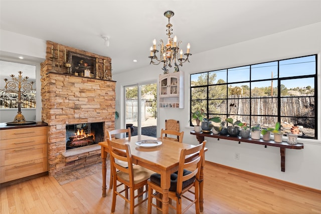 1115 N Luna Cir, Santa Fe, NM 87501 - dining room with light wood-type flooring, a fireplace, a chandelier, and baseboards