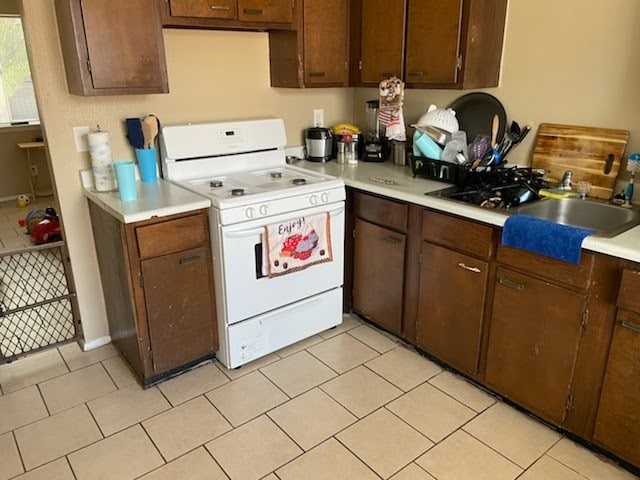 kitchen featuring white gas range, light countertops, and a sink