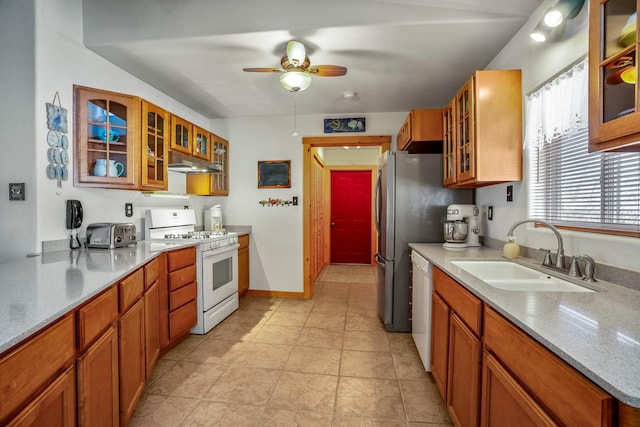 kitchen featuring glass insert cabinets, white appliances, a sink, and under cabinet range hood