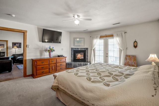 carpeted bedroom with french doors, visible vents, a ceiling fan, a high end fireplace, and access to outside