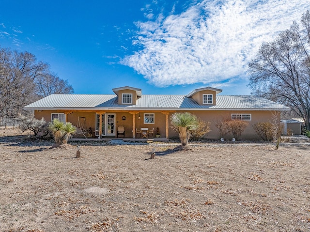 ranch-style home with a porch, metal roof, and stucco siding