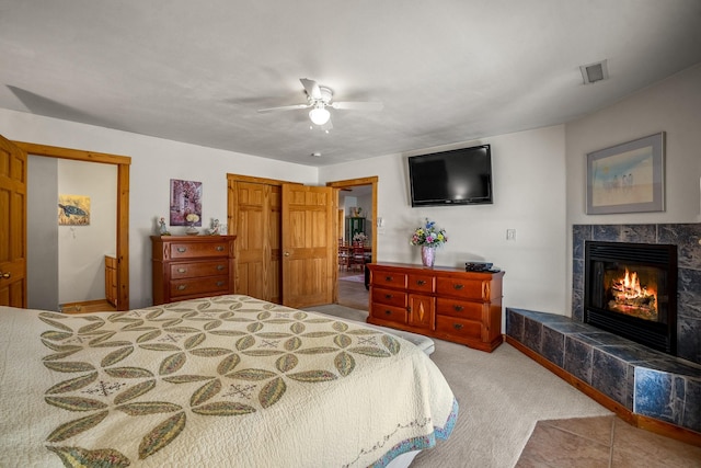 bedroom with visible vents, a tile fireplace, ceiling fan, carpet flooring, and a closet