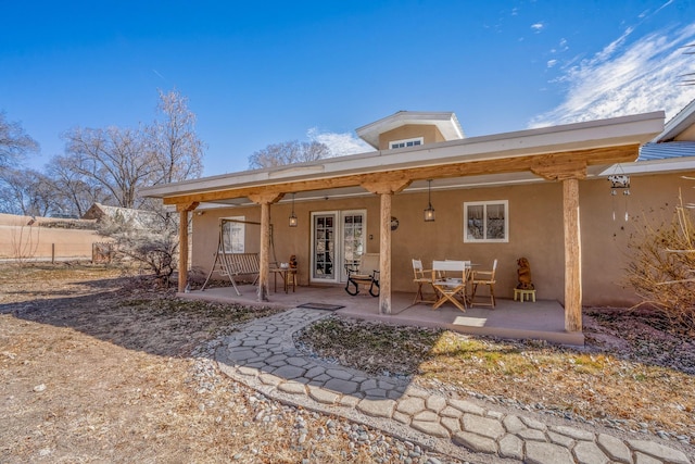 back of property with a patio area, french doors, and stucco siding