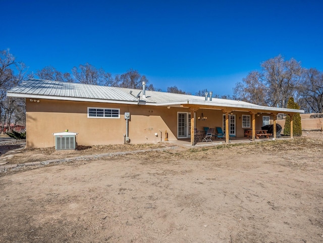 back of house featuring cooling unit, metal roof, a patio, and stucco siding