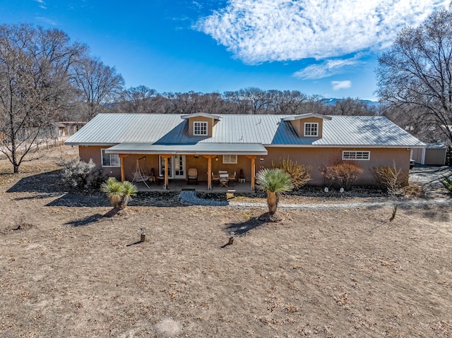 single story home featuring stucco siding, metal roof, and a patio