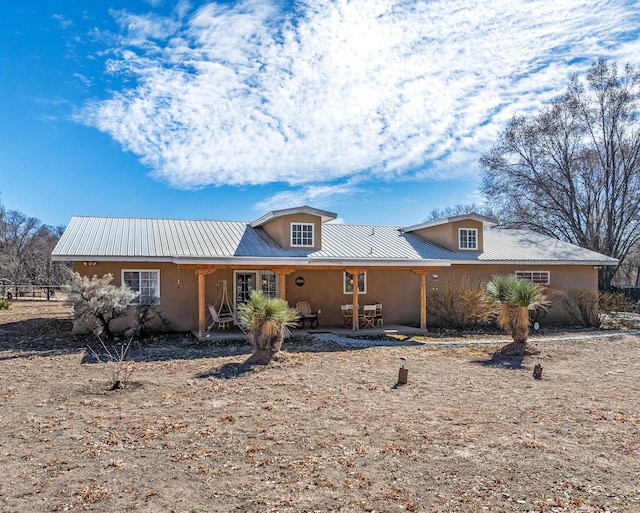 single story home featuring metal roof and stucco siding