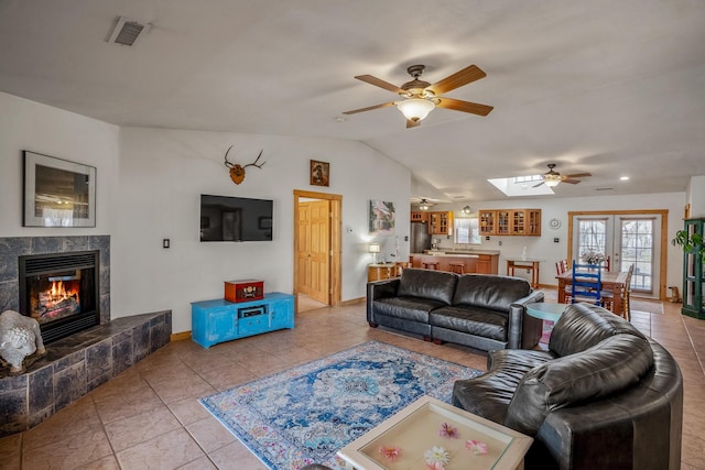 living area featuring light tile patterned floors, a fireplace, visible vents, and vaulted ceiling