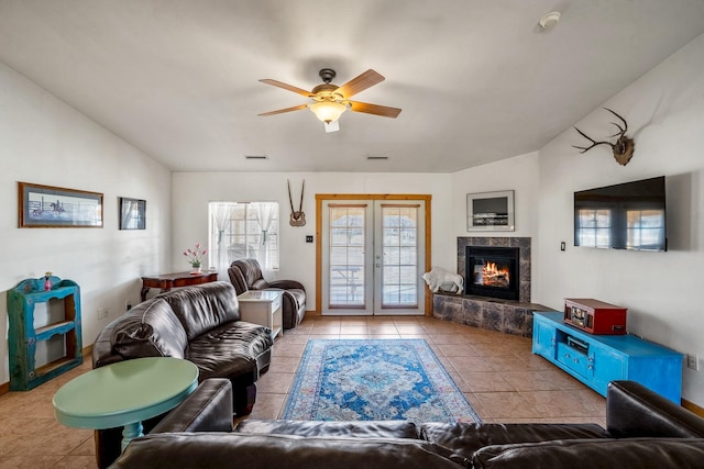 living area featuring french doors, visible vents, a tiled fireplace, vaulted ceiling, and tile patterned floors