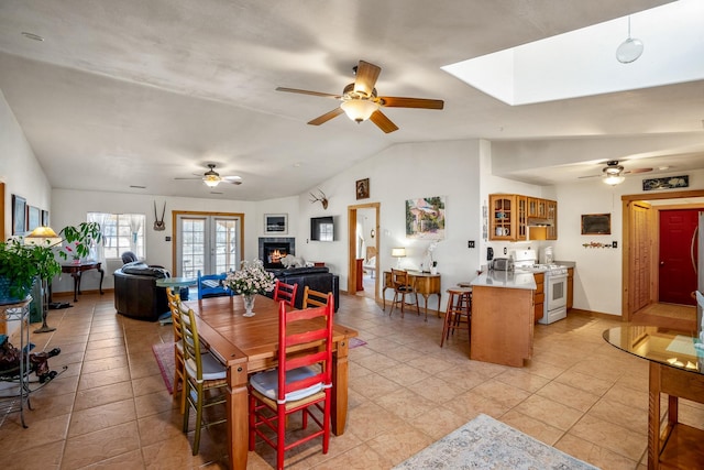 dining space with french doors, lofted ceiling with skylight, a ceiling fan, and baseboards