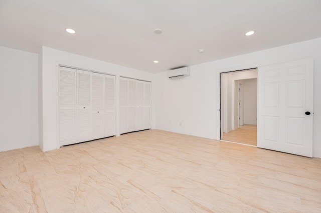 unfurnished bedroom with recessed lighting, a wall mounted air conditioner, and light wood-style flooring