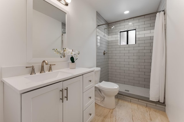 bathroom with vanity, a tile shower, and toilet