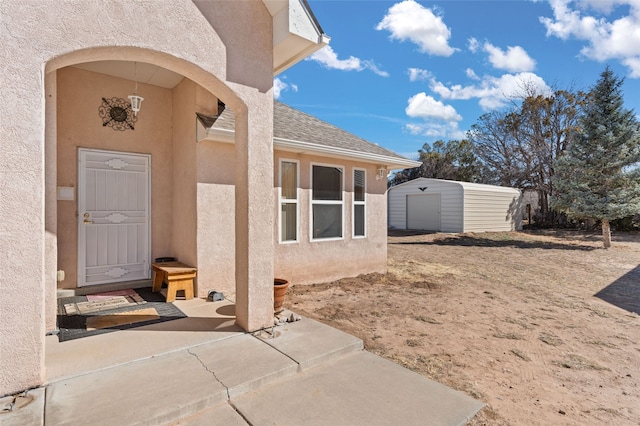 property entrance with a shingled roof and stucco siding