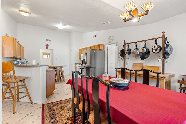 dining room featuring lofted ceiling, a textured ceiling, light tile patterned flooring, and visible vents