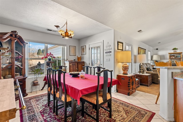 dining space with lofted ceiling, visible vents, a notable chandelier, and light tile patterned flooring