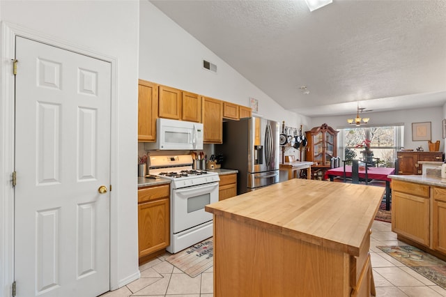 kitchen with white appliances, light tile patterned floors, visible vents, butcher block countertops, and a notable chandelier