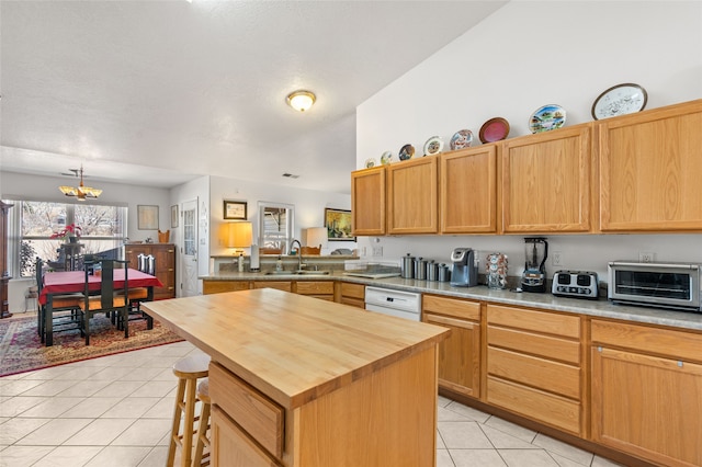 kitchen featuring a toaster, light tile patterned floors, wooden counters, a kitchen island, and a sink