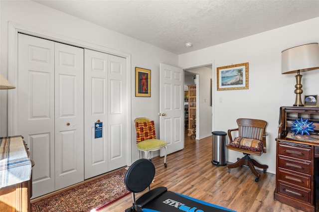 exercise area with a textured ceiling, baseboards, and wood finished floors