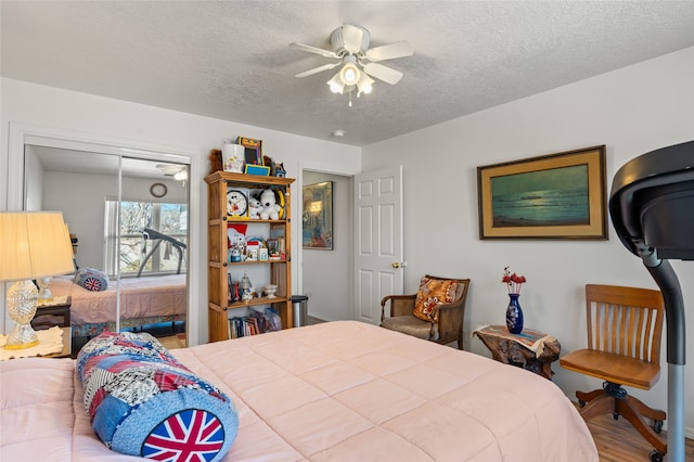 bedroom with a textured ceiling, ceiling fan, a closet, and wood finished floors