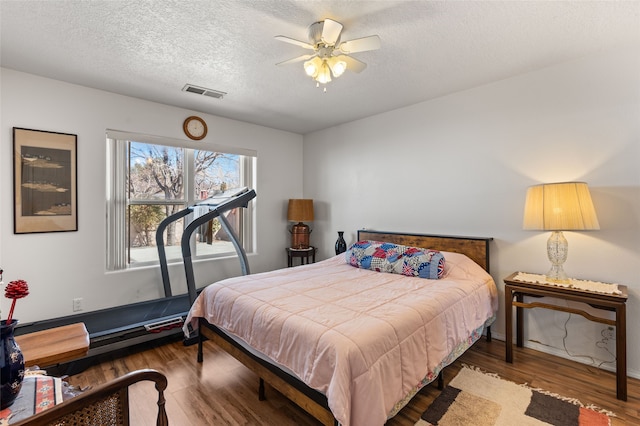 bedroom with visible vents, ceiling fan, a textured ceiling, and wood finished floors