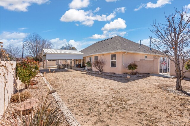 back of property featuring a carport, a fenced backyard, a shingled roof, and stucco siding