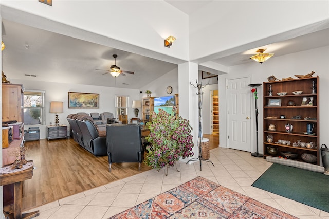 living area featuring lofted ceiling, light tile patterned floors, and ceiling fan