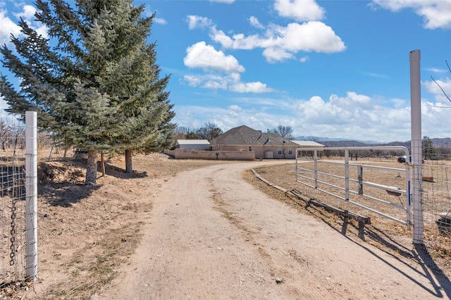 view of road featuring driveway, a gate, a gated entry, and a rural view