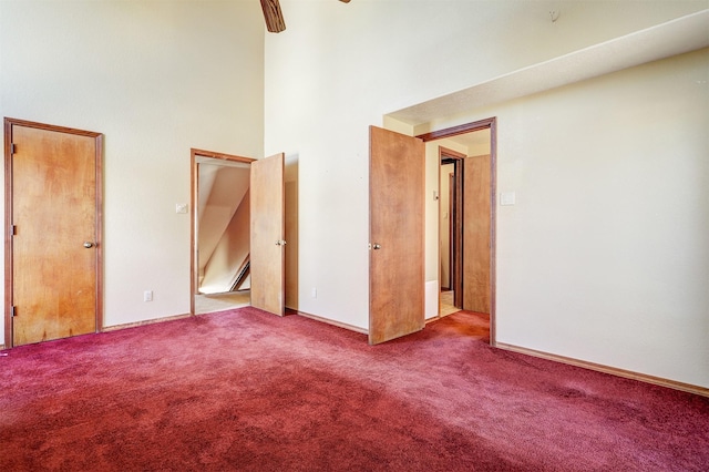 unfurnished bedroom with ceiling fan, carpet floors, and a towering ceiling