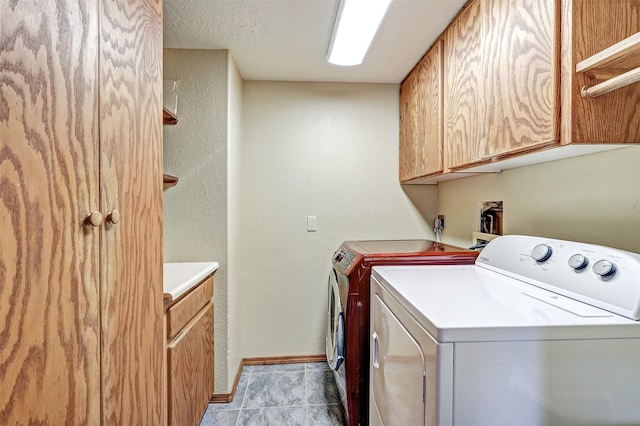 washroom featuring washer and clothes dryer, light tile patterned floors, cabinet space, a textured ceiling, and baseboards