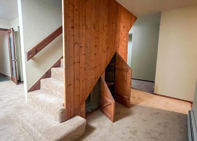 staircase featuring a baseboard radiator, baseboards, and carpet flooring