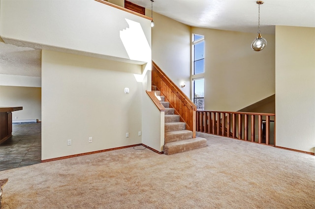 unfurnished living room with carpet, baseboards, stairway, and a high ceiling