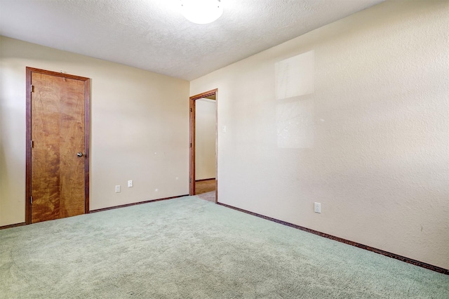 carpeted empty room with a textured ceiling and baseboards