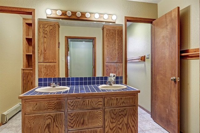 full bath with double vanity, tile patterned flooring, a baseboard heating unit, and a sink