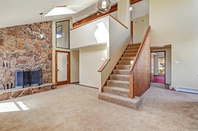 stairs featuring carpet floors, a baseboard radiator, high vaulted ceiling, and a stone fireplace