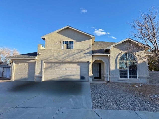 view of front of house featuring driveway, a balcony, roof with shingles, and stucco siding